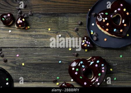 ciambelle con glassa al cioccolato su tavola di legno bianco, ciambelle a forma di cuore con smalto, ciambelle e cioccolato Foto Stock