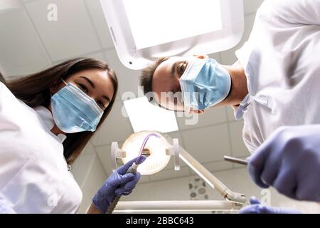 L'uomo guarda con gioia verso il basso. Ispezione presso il dentista dal punto di vista del paziente. Foto Stock