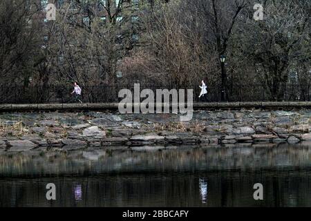 New York City, New York, Stati Uniti. 30th Mar, 2020. Due donne si divertiranno a correre nel Central Park di New York lunedì, marzo 30th. Oggi c'era un accenno di primavera in aria e le persone hanno cercato di sfruttare al meglio il parco centrale anche mentre nelle vicinanze del parco si stava costruendo un ospedale di emergenza in risposta alla pandemia del virus corona. Credito: Adam Stoltman/Alamy Live News Foto Stock