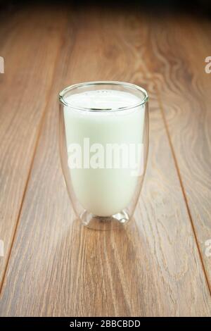 Bicchiere di latte per una colazione su un tavolo di legno spruzzi di latte. Foto Stock