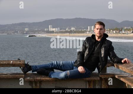 Attraente giovane uomo che si rilassa sul molo a Venice Beach California in vacanza Foto Stock