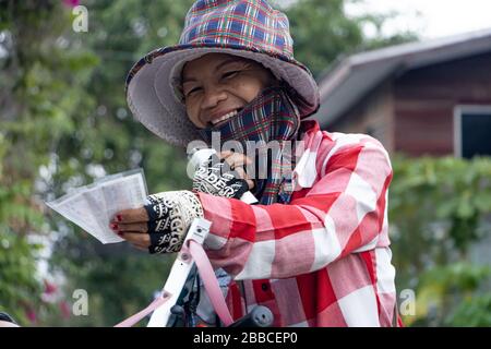 SAMUT PRAKAN, THAILANDIA, 14 MARZO 2020, Ritratto di una donna di vendita sorridente che offre biglietto della lotteria da un tavolo montato su una bicicletta. Foto Stock