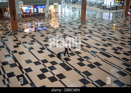 28.03.2020, Singapore, Repubblica di Singapore, Asia - pilota sulla sua strada per il controllo di sicurezza nella sala partenze altrimenti deserta all'Aeroporto di Changi. Foto Stock