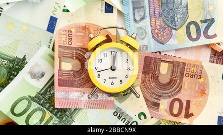 Sveglia con carta euro moneta 10, 20, 50, 100, sveglia su banconote, tempo è denaro Foto Stock