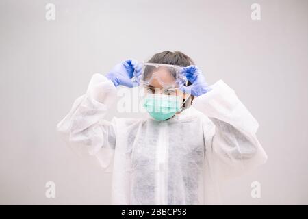 Infermiere giovane con tuta monouso indossando guanti sterili preparazione cura di Coronavirus 2019-nCoV pandemico 2019. Foto Stock