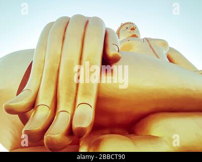 Vicino a mano di grande statua del Buddha con cielo blu a Wat Tha Muang Thailandia. Le statue più iconiche del Buddha d'oro Foto Stock