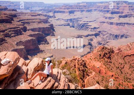 Young Woman si trova sul bordo DI una roccia, il Grand Canyon, Arizona, Stati Uniti Foto Stock