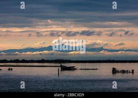 Tramonto sulla Laguna di grado, con le Dolomiti oltre, Friuli-Venezia Giulia, Italia Foto Stock