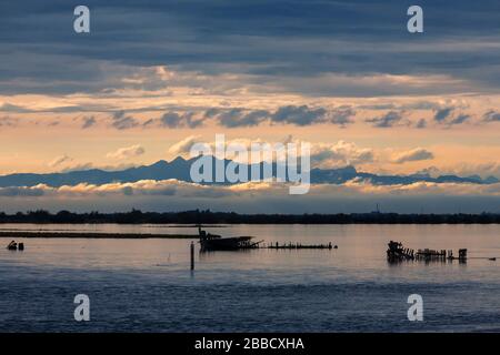 Tramonto sulla Laguna di grado, con le Dolomiti oltre, Friuli-Venezia Giulia, Italia Foto Stock