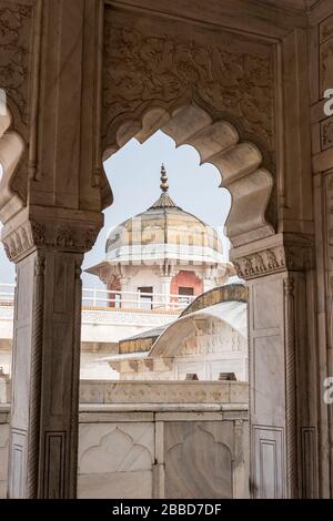 Vista di una torre attraverso un elaborato arco al Forte di Agra in India Foto Stock