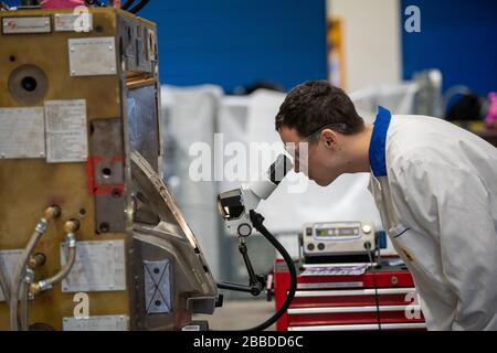 il tecnico controlla la corretta impostazione dello stampo metallico per i pezzi fusi in fabbrica utilizzando un microscopio Foto Stock