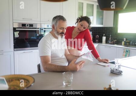 Sorridente coppia consultando un libro in cucina. Foto Stock