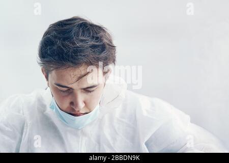 Triste dottore stanco con la testa giù dopo un duro lavoro di giornata. Uomo in tuta protettiva. Pandemia epidemica nuova diffusione rapida del coronavirus 2019-ncov, Foto Stock