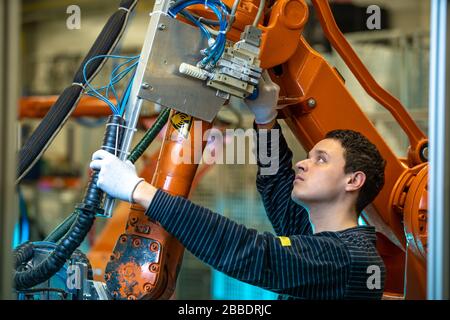 robotizzazione dell'industria moderna in fabbrica. Introduzione di nuovi bracci robotici per sostituire le risorse umane Foto Stock