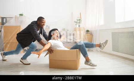 Marito americano africano che rotola sua moglie in scatola di cartone Foto Stock
