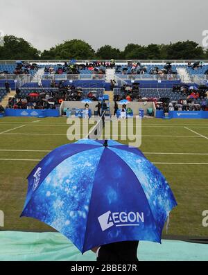 Gli spettatori prendono la copertura sotto gli ombrelli mentre il personale a terra si prepara a portare le coperture sul campo centrale prima di qualsiasi gioco nella semifinale tra Magdelana Rybarikova e Donna Vekic. Foto Stock