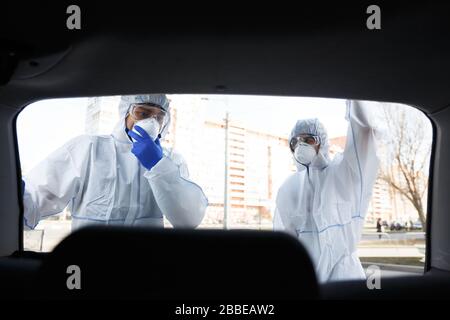 Lavoratore medico in tuta protettiva virus aprire tronco e guardare Foto Stock