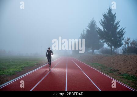 Atleta in pista con linee rosse sopra il cielo blu nebbia. Foto sportiva, spazio di editing Foto Stock