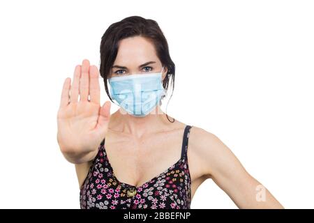 Donna che indossa la maschera protettiva del viso facendo un segno di stop con la mano. Isolato su bianco. Foto Stock