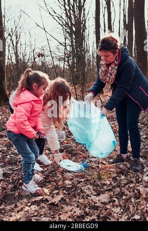 Famiglia pulizia su una foresta. I volontari prelevano i rifiuti di plastica ai sacchetti. Concetto di inquinamento della plastica e troppi rifiuti di plastica. Problema ambientale. E Foto Stock