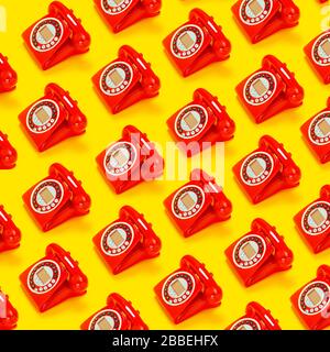 Un telefono rosso retrò su sfondo giallo. Foto Stock