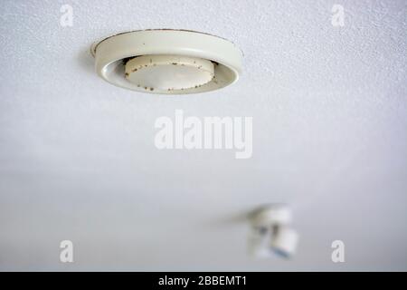 Vecchio giallo sporco usato valvola di ventilazione a soffitto coperta di polvere e stampo. Macchie di luce sullo sfondo Foto Stock