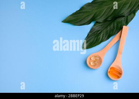 Supplementi sani su cucchiaini di legno su sfondo blu Foto Stock