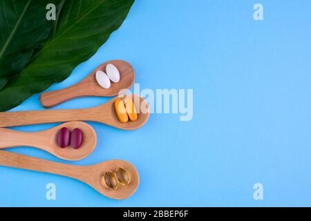 Supplementi sani su cucchiaini di legno su sfondo blu Foto Stock