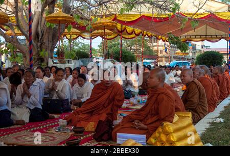 Kambot, Cambogia, Asia: Monaci buddisti e fedeli seduti in preghiera in un tempio esterno della città Foto Stock