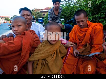 Kambot, Cambogia, Asia: Alcuni giovani studenti buddisti siedono in gruppo mentre giocano con un tablet Foto Stock