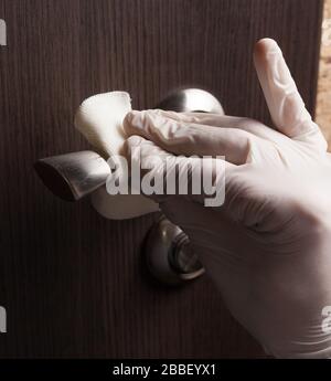 Primo piano di disinfezione, pulizia e lavaggio delle maniglie delle portiere in guanti bianchi. Prevenzione delle infezioni da coronavirus Foto Stock