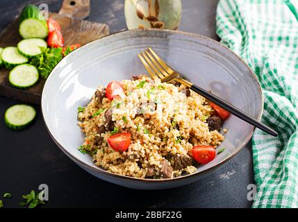 Pilaf bulgur con carne e verdure. Delizioso e salutare pranzo caldo su sfondo nero. Cucina orientale. Foto Stock