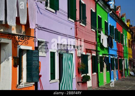 Vista ravvicinata di una sezione di uno dei vecchi edifici di Burano vicino a Venezia con facciata colorata e appendiabiti per lavanderia Foto Stock