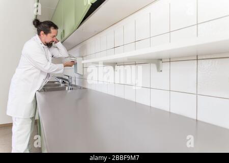 il medico maschio sta lavando le sue mani con sapone, poi usa liquido di disinfezione, concetto di virus corona o covid-19, sars-cov-2 Foto Stock