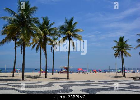 Rio de Janeiro, Brasile - Febbraio 2019; vista mare della spiaggia di Ipanema con di fronte il marciapiede mosaico fiancheggiato da palme Foto Stock