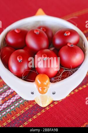 Piatto pieno di uova di Pasqua rosse sul tavolo Foto Stock