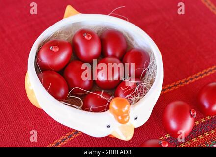 Piatto pieno di uova di Pasqua rosse sul tavolo Foto Stock