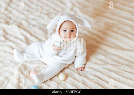 bambino piccolo sorridente bambino in un coniglio bunny bianco costume pasqua giocando con le uova di pasqua colorate Foto Stock