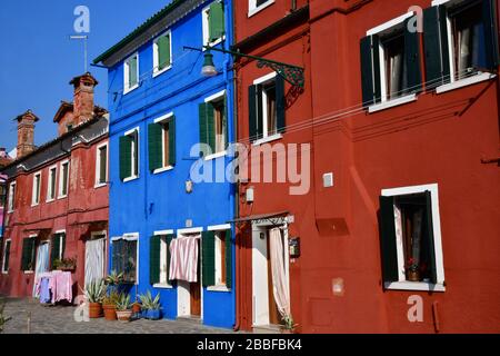 Vista ad angolo basso di alcune delle case colorate di Burano in una giornata di sole con cielo blu chiaro Foto Stock