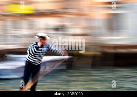 Vista in movimento estremamente sfocata di primo piano del gondoliere veneziano al lavoro mentre parla sul suo telefono cellulare allo stesso tempo il suo braccio in movimento tipico a m. Foto Stock