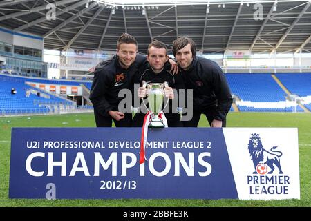 L'assistente sportivo di Charlton Athletic lo scienziato sportivo Jared Roberts-Smith (a sinistra) e l'accademia phiso Pete Webb (a destra) accanto al manager Nathan Jones (al centro) posano per una fotografia con il trofeo Foto Stock