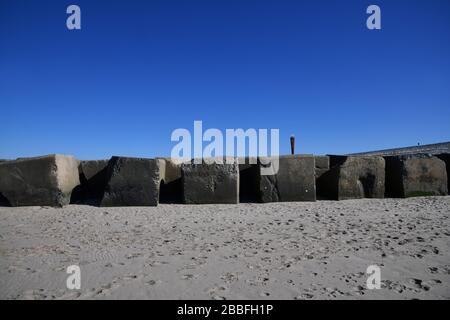 Maasvlakte Beach, Rotterdam, Paesi Bassi - Marzo 2020: Vista a basso angolo di grandi blocchi di cemento sulla spiaggia in una giornata di sole con un iconico Foto Stock