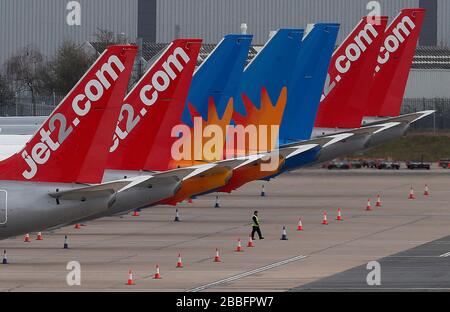 Birmingham, West Midlands, Regno Unito. 31st marzo 2020. Un lavoratore cammina sotto gli aerei Jet2 parcheggiati sul asfalto all'aeroporto di Birmingham durante il blocco pandemico di Coronavirus. Credit Darren Staples/Alamy Live News. Foto Stock