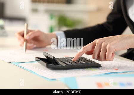 Primo piano di executive donne mani calcolo con calcolatrice su una scrivania in ufficio Foto Stock