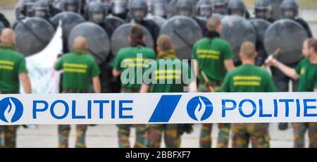 Politie / nastro di polizia di fronte a manifestanti e squadra antisommossa belga formando una barriera protettiva con scudi antisommossa Foto Stock