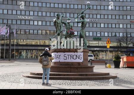 (200331) -- HELSINKI, 31 marzo 2020 (Xinhua) -- un cittadino scatta un'immagine della famosa scultura cittadina 'Three Smiths' che è stata indossata su maschere facciali, a Helsinki, Finlandia, 31 marzo 2020. A partire da lunedì, i casi di coronavirus in Finlandia si attestavano a 1.313 morti, secondo l'Istituto finlandese per la salute e il benessere (THL). (Xinhua/Zhu Haochen) Foto Stock