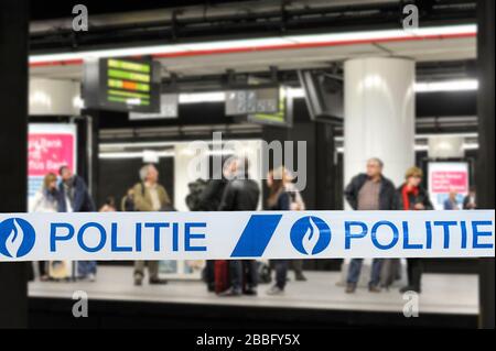 Politie / nastro di polizia di fronte ai pendolari in attesa di treno alla piattaforma della stazione ferroviaria belga in Belgio Foto Stock