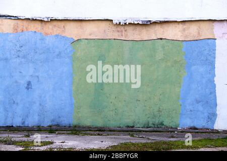 un colorato verde e blu dipinto vecchio magazzino muro fabbrica in un vicolo Foto Stock