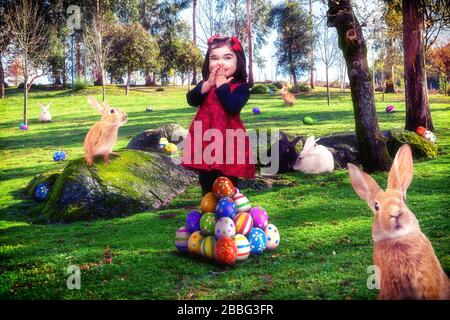 Bambina raccolta e raccolta colorate uova di Pasqua parco prato Pasqua coniglietti Pasqua uovo caccia gioco. Felice bambino prescolare ragazza sorridente Foto Stock