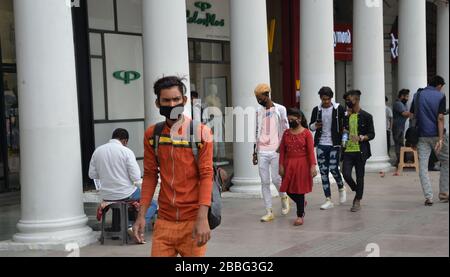 Le persone che indossano maschere facciali camminano nel complesso dello shopping Connaught Place a Nuova Delhi, India. I mercati sono in gran parte deserti con i negozi chiusi come le persone sono s. Foto Stock